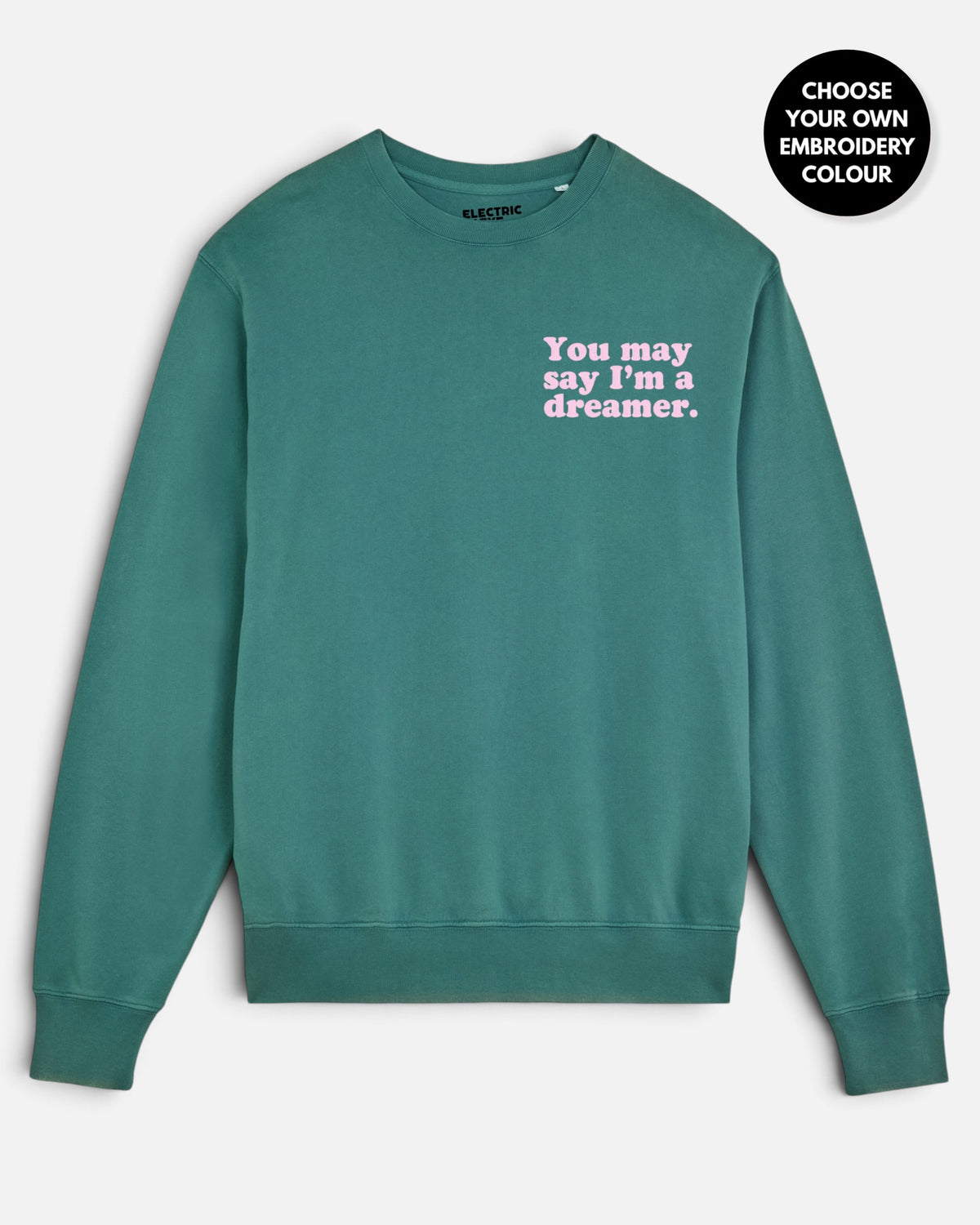 A teal crewneck sweatshirt with the text 'You may say I'm a dreamer.' embroidered in pink on the chest.